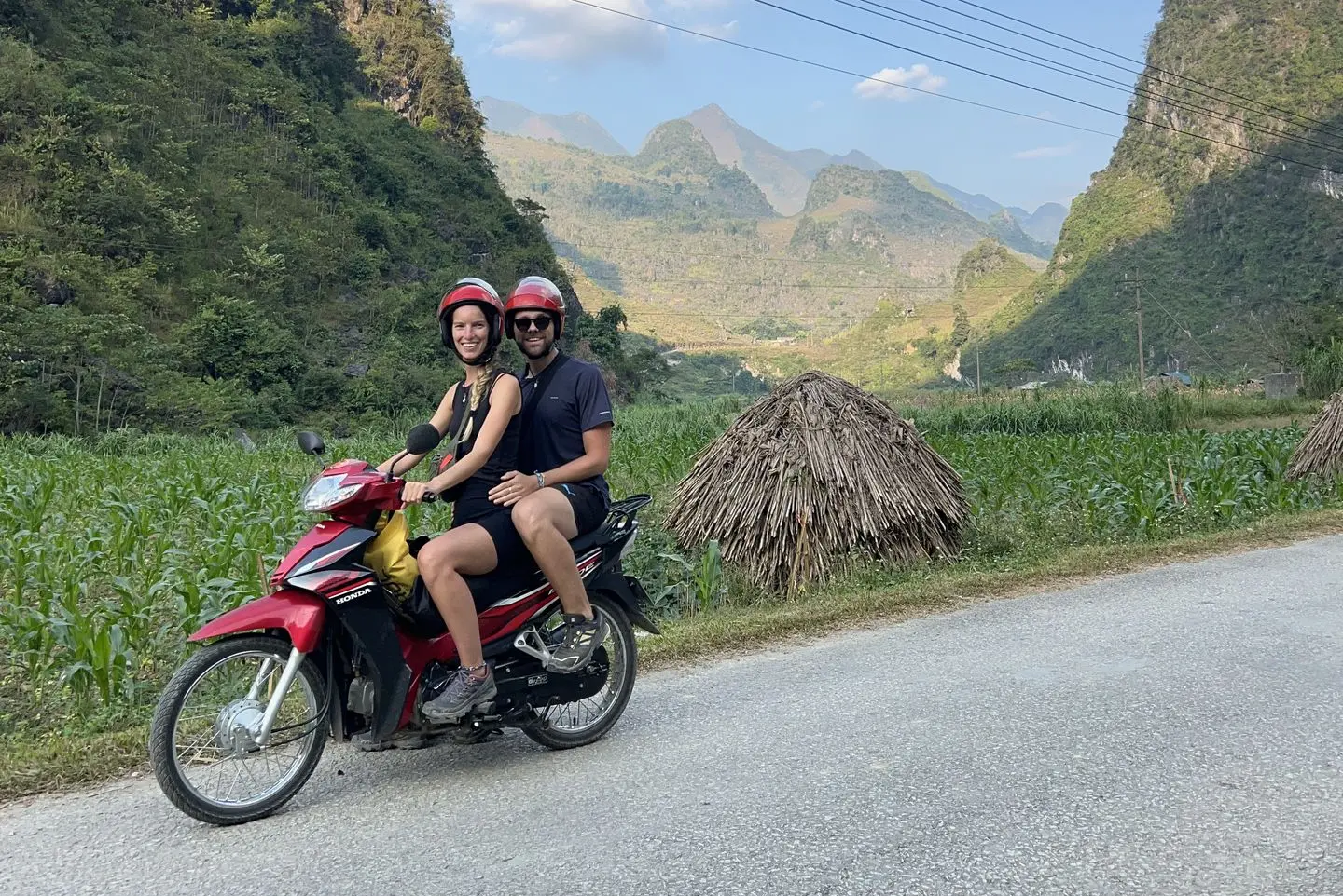 Carola and Martín riding a scooter through green karst mountains
