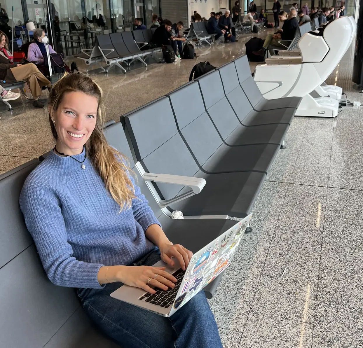 Carola writing a travel guide on her laptop at an airport gate